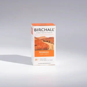 The Birchall Organic Redbush Caffeine-free Tea Bags are presented in a box against a white background, ideal for any café atmosphere. The packaging showcases an orange mountain design with the words "Sweet & Earthy" and "15 Prism Tea Bags." A "Great Taste" award logo emphasizes its quality, making it a top pick for baristas.