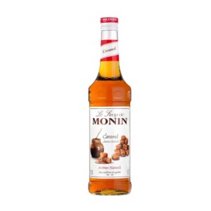 A clear glass bottle of Monin caramel syrup with a red and white label, perfect for any café or barista, featuring images of caramel cubes. The bottle is filled with amber-colored syrup, and the label text is in French.