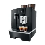 The Jura GIGA X8 Pro Gen II Black Tanked Bean to Cup Coffee Machine, reminiscent of a café barista's setup, is an automatic espresso machine featuring a digital display and dual coffee spouts for making two espresso shots simultaneously. Two containers filled with coffee beans rest on top, while two glass cups eagerly await the rich brew below the spouts.