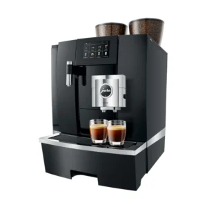 The Jura GIGA X8 Pro Gen II Black Tanked Bean to Cup Coffee Machine, reminiscent of a café barista's setup, is an automatic espresso machine featuring a digital display and dual coffee spouts for making two espresso shots simultaneously. Two containers filled with coffee beans rest on top, while two glass cups eagerly await the rich brew below the spouts.