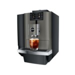 The Jura X10 Dark Inox - Tanked Bean to Cup Coffee Machine, with its sleek black and silver finish and digital display, is brewing a glass of iced coffee that rivals café quality. Its modern design, complete with the "Jura" logo, complements the skills of any barista.